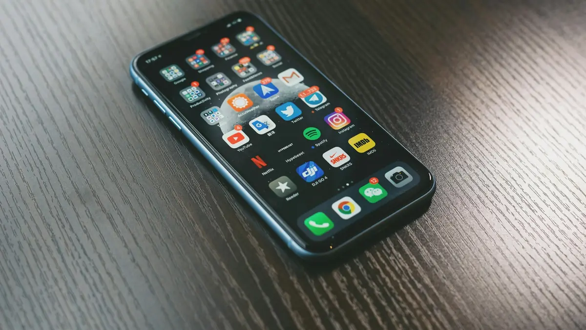 Smartphone with a home screen of app icons on a wooden table