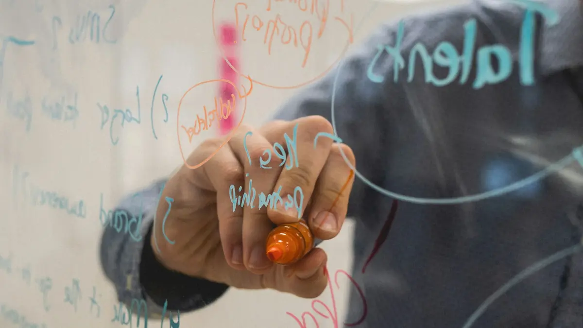 Person drawing a system diagram on a glass whiteboard
