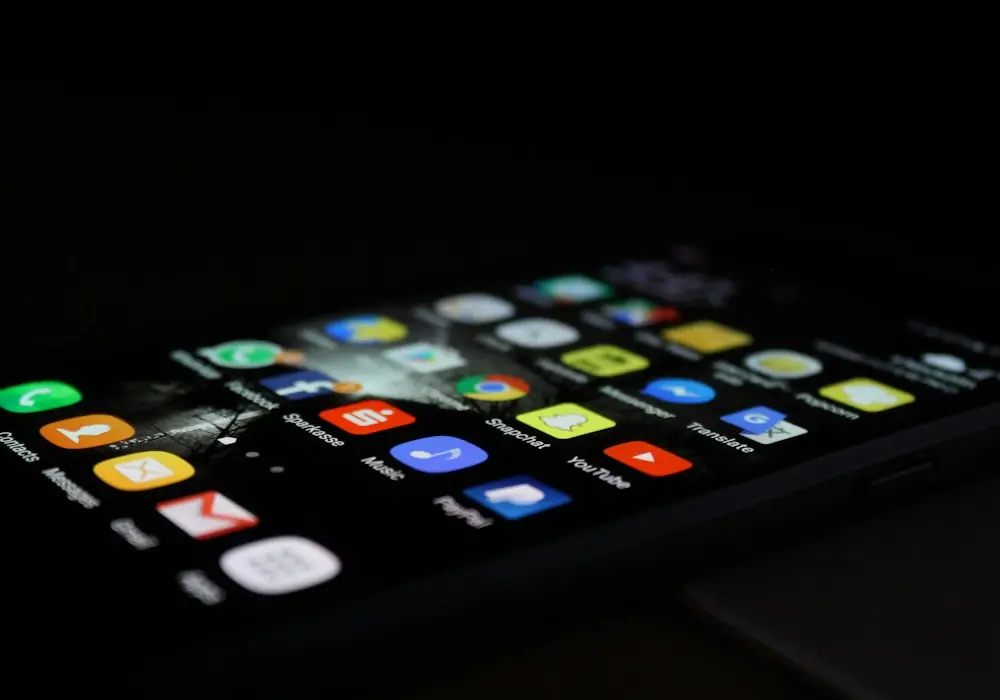 Smartphone screen with app icons in a dark room